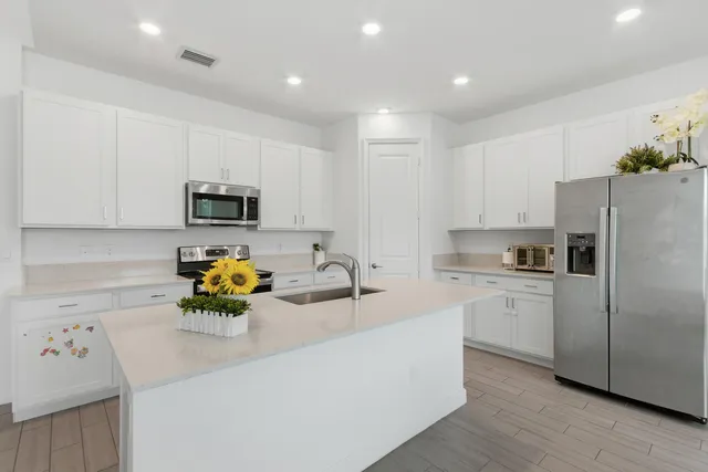 a kitchen with a sink a stove a microwave a refrigerator a white table and chairs