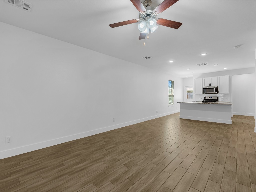 24751 Russet Bluff Trail Houston, TX 77336 - Photo 7 of 26 an empty room with wooden floor a ceiling fan and kitchen view