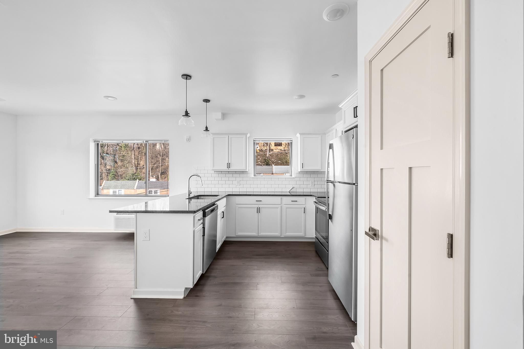 a kitchen with stainless steel appliances a refrigerator and white cabinets
