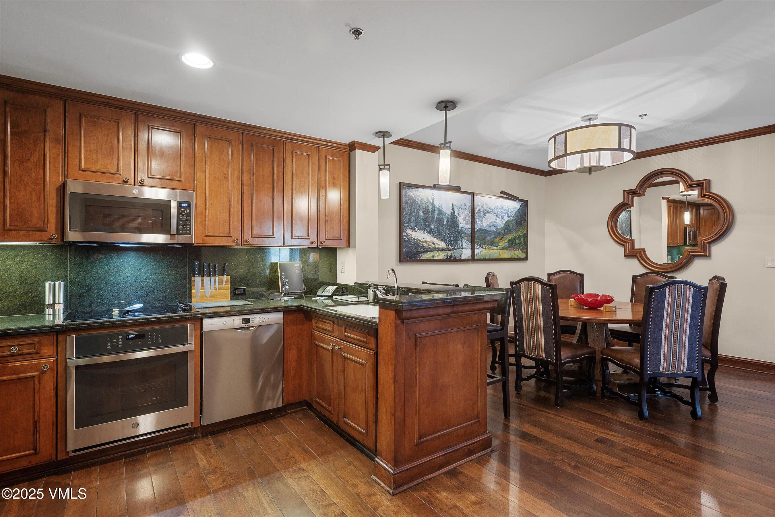 39 Boomerang Road, Unit 841114 Aspen, CO 81611 - Photo 16 of 35 a kitchen with stainless steel appliances granite countertop a stove top oven a sink dishwasher a dining table and chairs with wooden floor