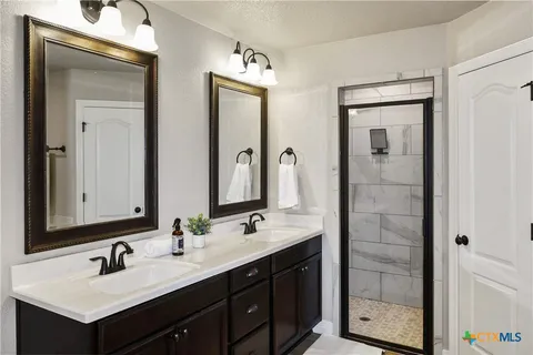 a bathroom with a double vanity sink mirror and shower