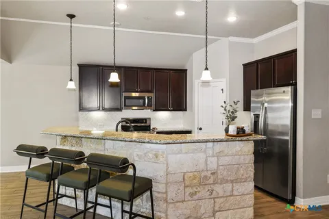 a kitchen with stainless steel appliances granite countertop a sink a stove a refrigerator a center island a stove and cabinets