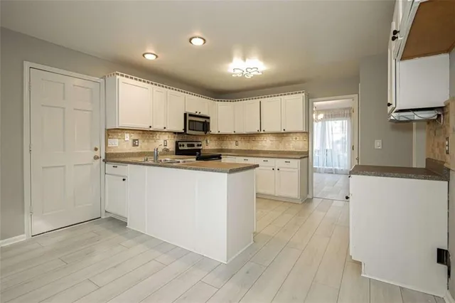 a kitchen with stainless steel appliances white cabinets and wooden floor