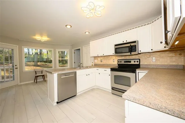 a kitchen with granite countertop white cabinets and white stainless steel appliances