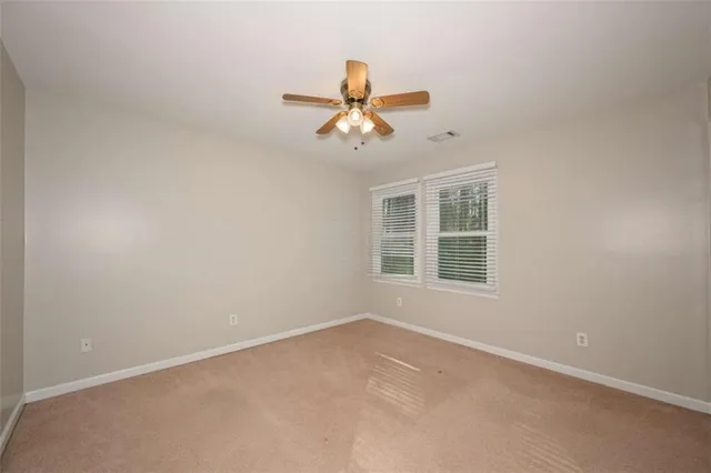 a view of an empty room with a window and a ceiling fan