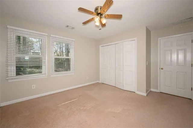 an empty room with closet and a ceiling fan