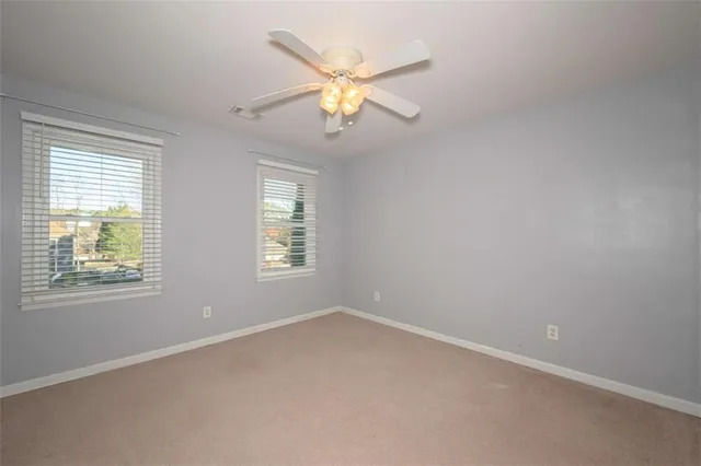 an empty room with a chandelier fan and closet area
