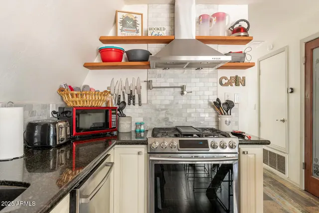 a kitchen with stainless steel appliances granite countertop a stove and a wooden floor