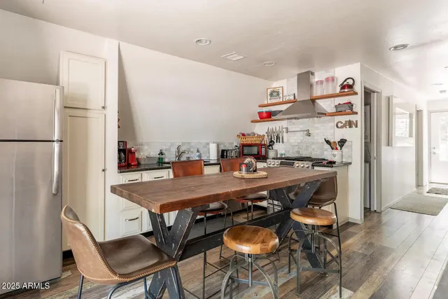 a kitchen with stainless steel appliances a dining table chairs and refrigerator