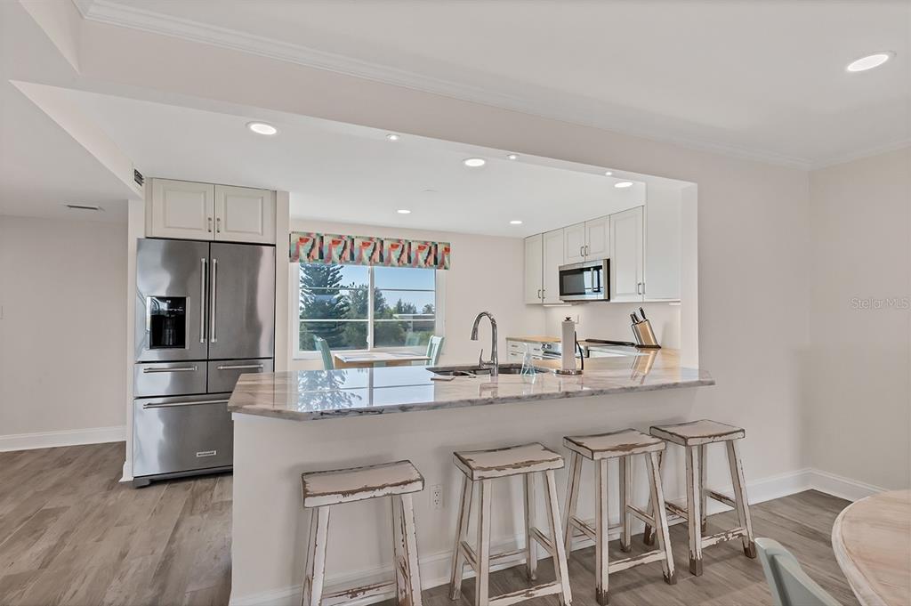 9397 Midnight Pass Road, Unit 501 Sarasota, FL 34242 - Photo 11 of 45 a kitchen with stainless steel appliances granite countertop a kitchen island a stove a table and chairs