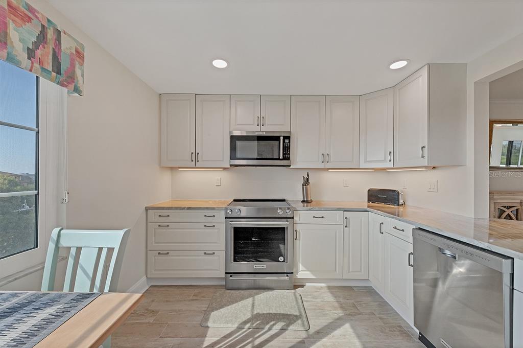 9397 Midnight Pass Road, Unit 501 Sarasota, FL 34242 - Photo 16 of 45 a kitchen with granite countertop a stove a sink and a refrigerator