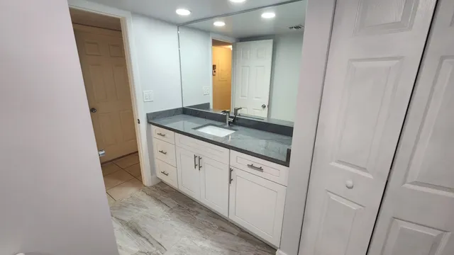 a bathroom with a granite countertop sink and a mirror