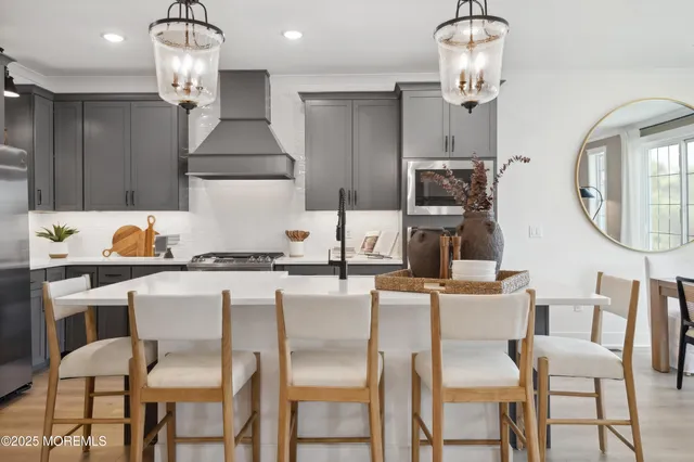 a kitchen with stainless steel appliances granite countertop a stove a dining table chairs and a chandelier