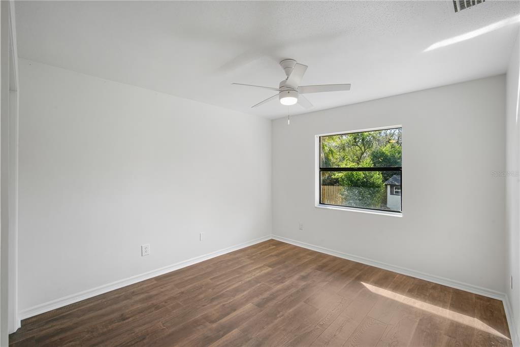 109 Holly Tree Lane Brandon, FL 33511 - Photo 23 of 31 an empty room with wooden floor ceiling fan and windows