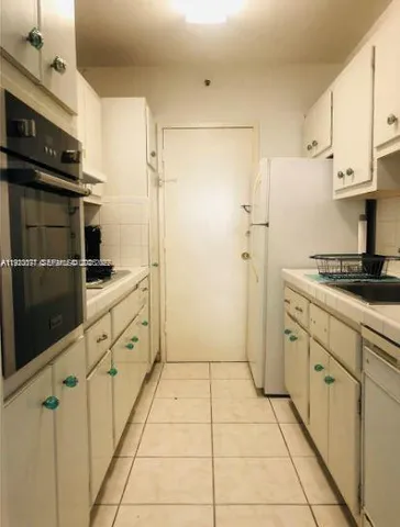 a kitchen with granite countertop a refrigerator and a stove top oven