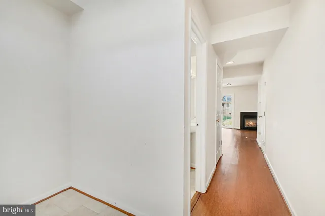 a view of a hallway with wooden floor and a bathroom