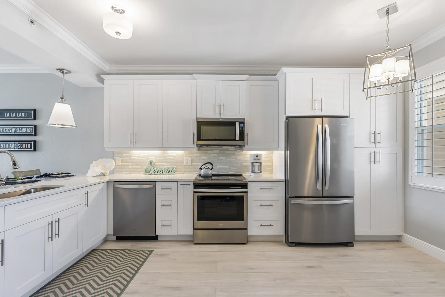 3780 Sawgrass Way, Unit 3325 Naples, FL 34112 - Photo 4 of 49 a kitchen with white cabinets and stainless steel appliances