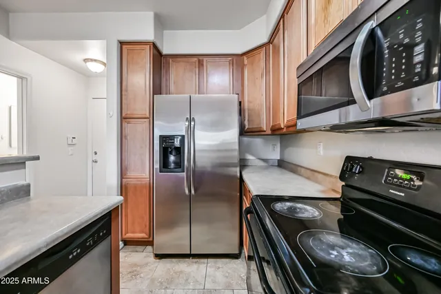 a kitchen with stainless steel appliances granite countertop a refrigerator a stove and a sink