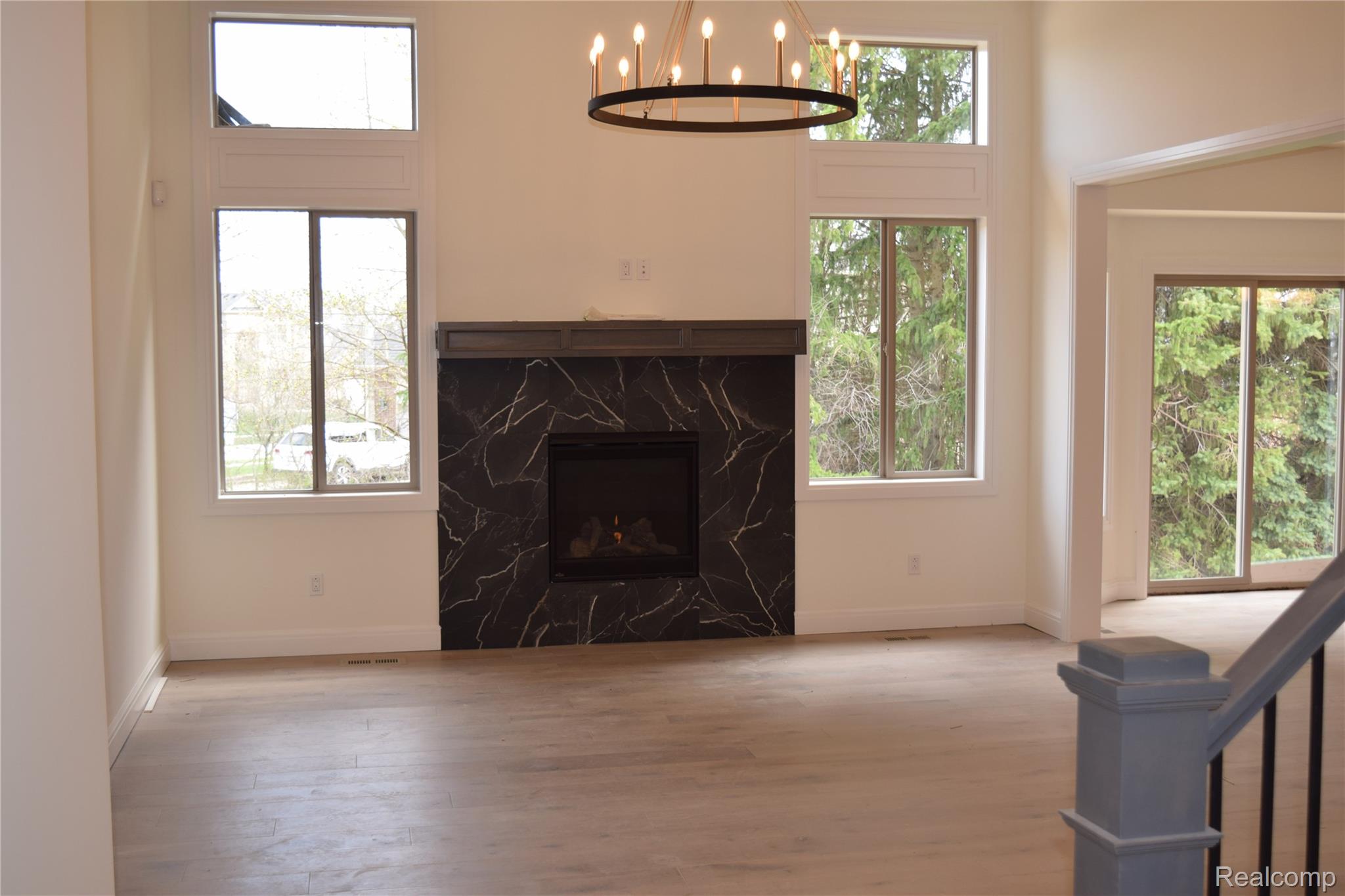 3093 Raffler Drive Rochester, MI 48307 - Photo 16 of 34 Living area featuring a fireplace, wood finished floors, a towering ceiling, and a chandelier