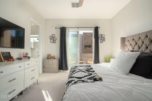 a bedroom with a large bed and a flat tv screen on dresser