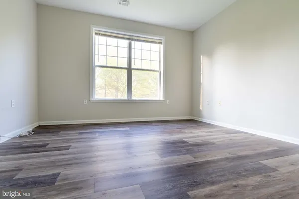 a view of an empty room with wooden floor and closet