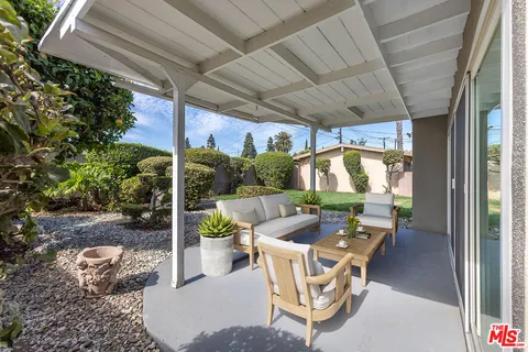 a patio with table and chairs and potted plants