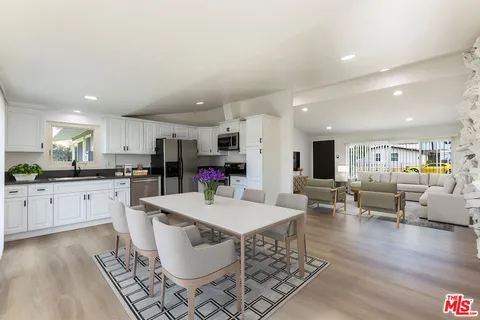 a large white kitchen with lots of counter space a sink appliances and dining table