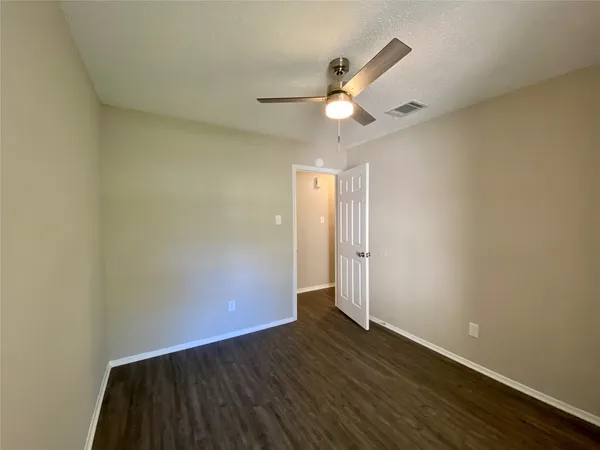 an empty room with wooden floor fan and windows