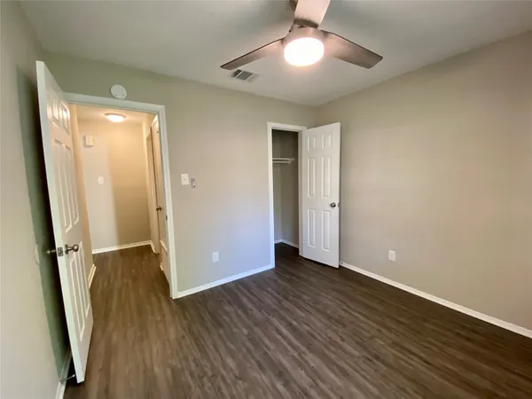an empty room with wooden floor and a ceiling fan