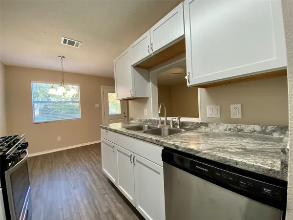 a kitchen with granite countertop stainless steel appliances a sink window and wooden floor