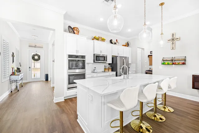 a kitchen with stainless steel appliances a refrigerator a stove a microwave a dining table and chairs with wooden floor