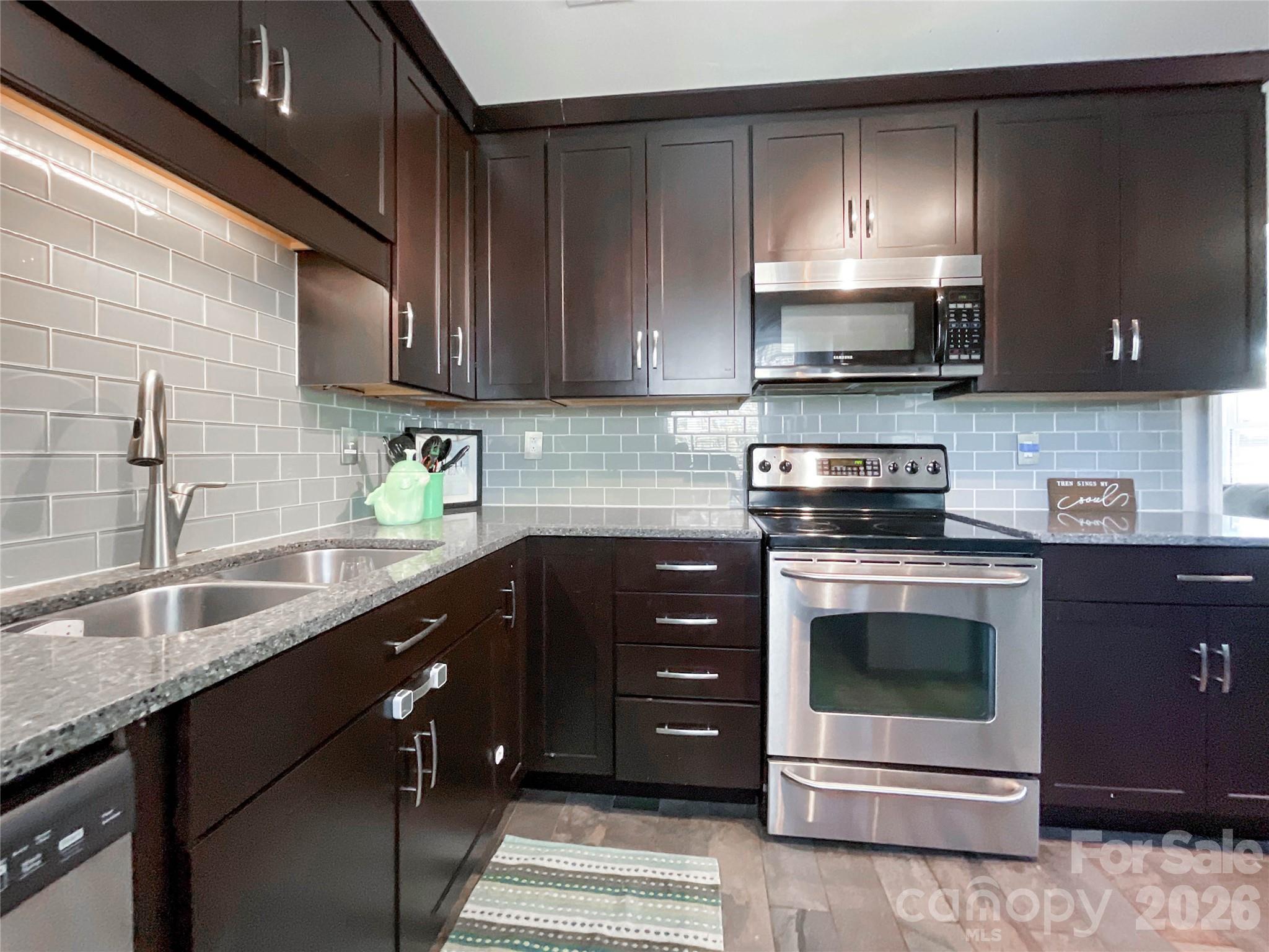 8004 Idlewild Road Indian Trail, NC 28079 - Photo 4 of 33 a kitchen with stainless steel appliances granite countertop a sink a stove and a microwave