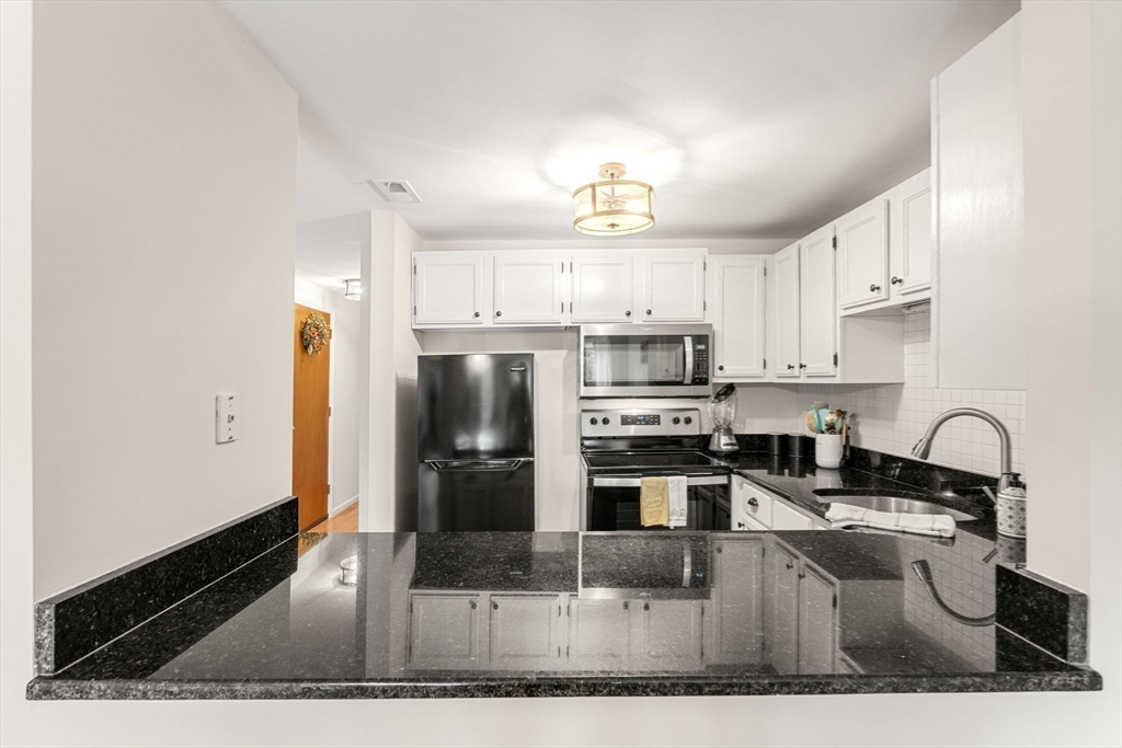 30 Conant Street, Unit 2D Beverly, MA 01915 - Photo 6 of 17 a kitchen with stainless steel appliances granite countertop a stove a sink dishwasher a refrigerator and a microwave with wooden floor