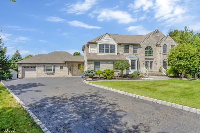 a view of a yard in front of a house with plants and large tree