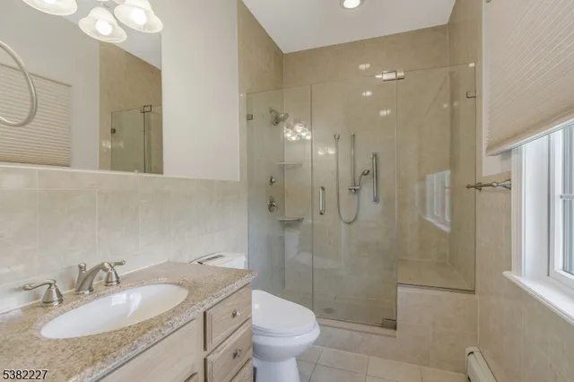 a bathroom with a granite countertop sink a toilet and shower