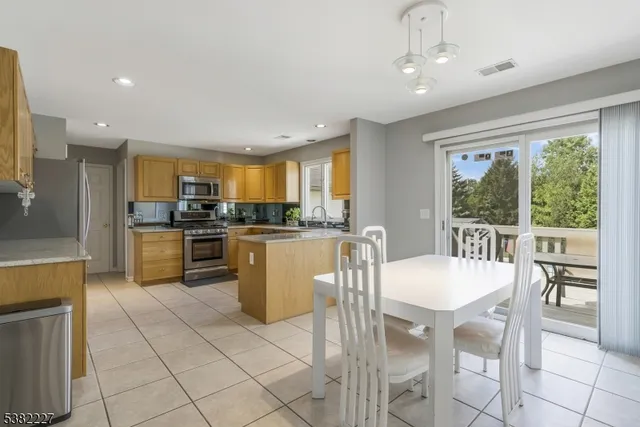 a kitchen with stainless steel appliances granite countertop a stove a refrigerator a kitchen island a table and chairs in it