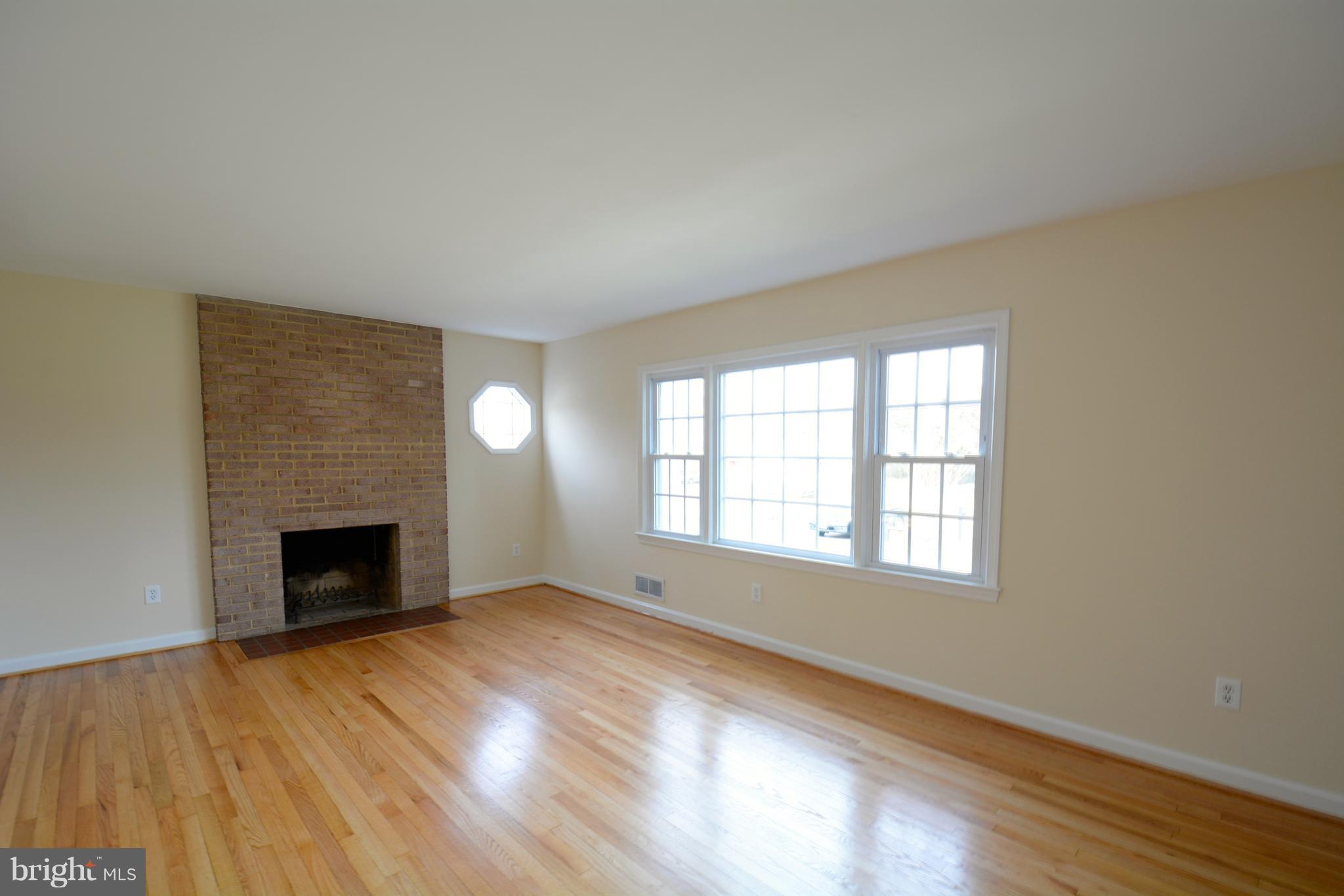 6505 Kalmia Street Springfield, VA 22150 - Photo 12 of 30 an empty room with wooden floor fireplace and windows