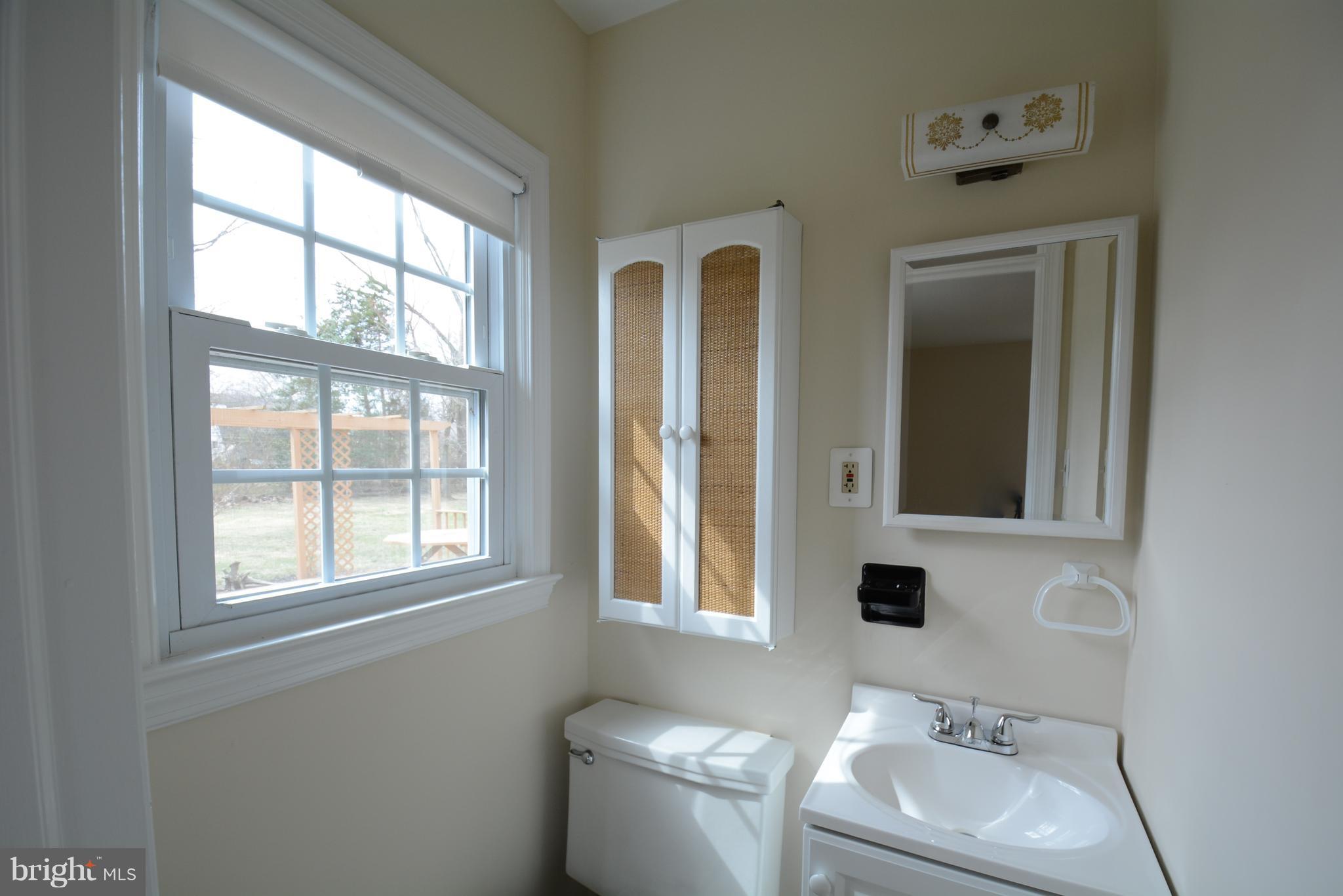 6505 Kalmia Street Springfield, VA 22150 - Photo 20 of 30 a bathroom with a toilet sink and mirror next to window