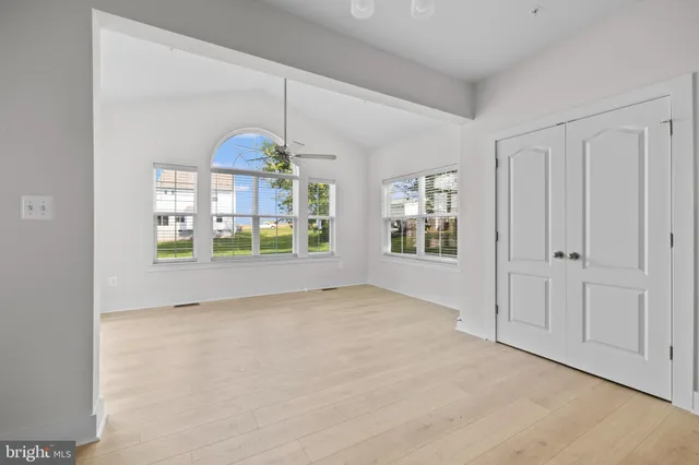 a view of an empty room with window and chandelier fan