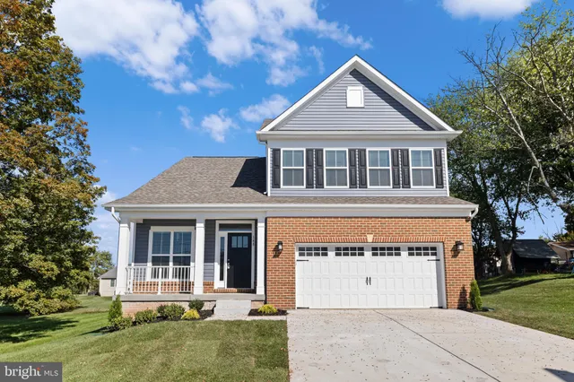 a front view of a house with a garden and trees
