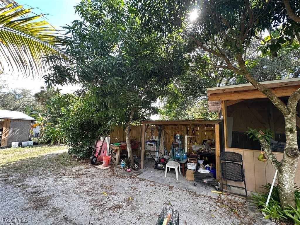 9320 Buckingham Road Fort Myers, FL 33905 - Photo 4 of 19 a view of a patio with table and chairs under an umbrella with large trees