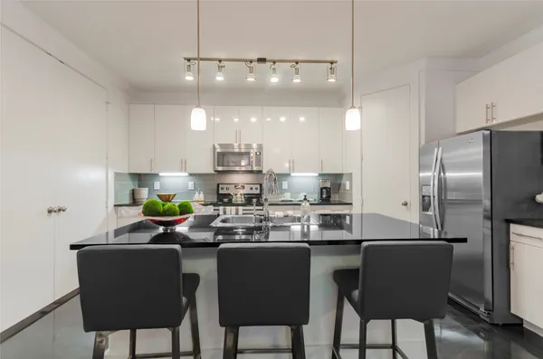 a kitchen with stainless steel appliances a dining table chairs refrigerator and sink