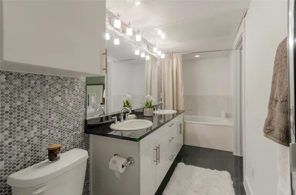 a bathroom with a double vanity sink toilet and shower