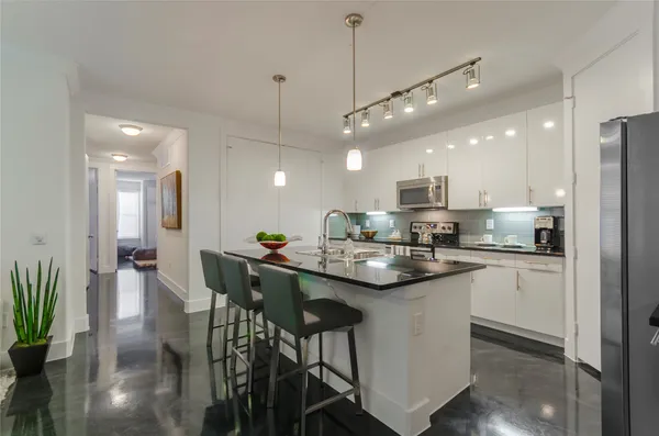 a kitchen with stainless steel appliances kitchen island granite countertop a dining table chairs and white cabinets