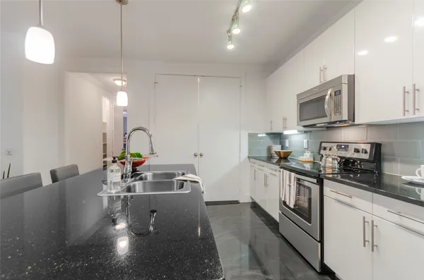 a kitchen with stainless steel appliances granite countertop a sink a stove and a wooden floors
