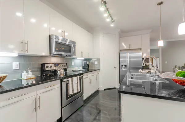 a kitchen with stainless steel appliances granite countertop a sink a stove and a refrigerator