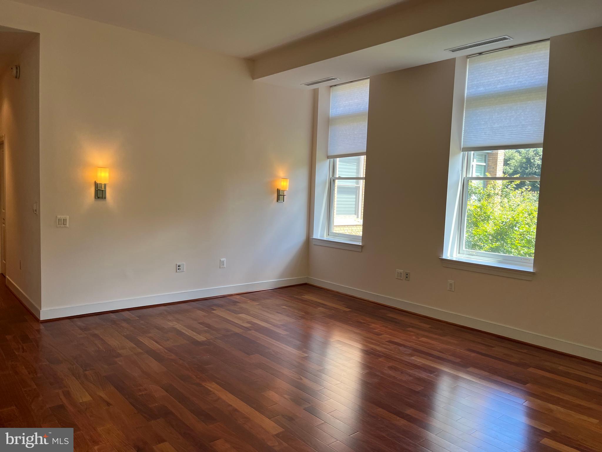 2425 L Street Northwest, Unit 215 Washington, DC 20037 - Photo 11 of 38 an empty room with wooden floor and windows