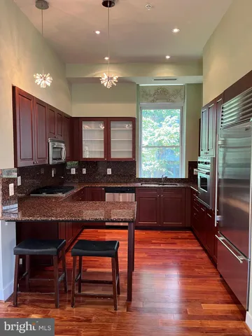 a kitchen with granite countertop wooden cabinets dining table and stainless steel appliances