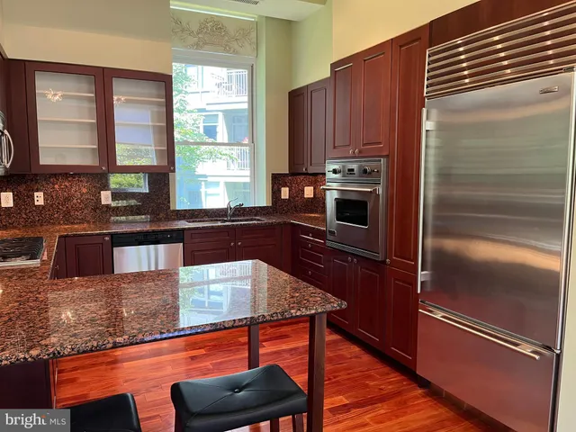 a kitchen with granite countertop a refrigerator and wooden cabinets
