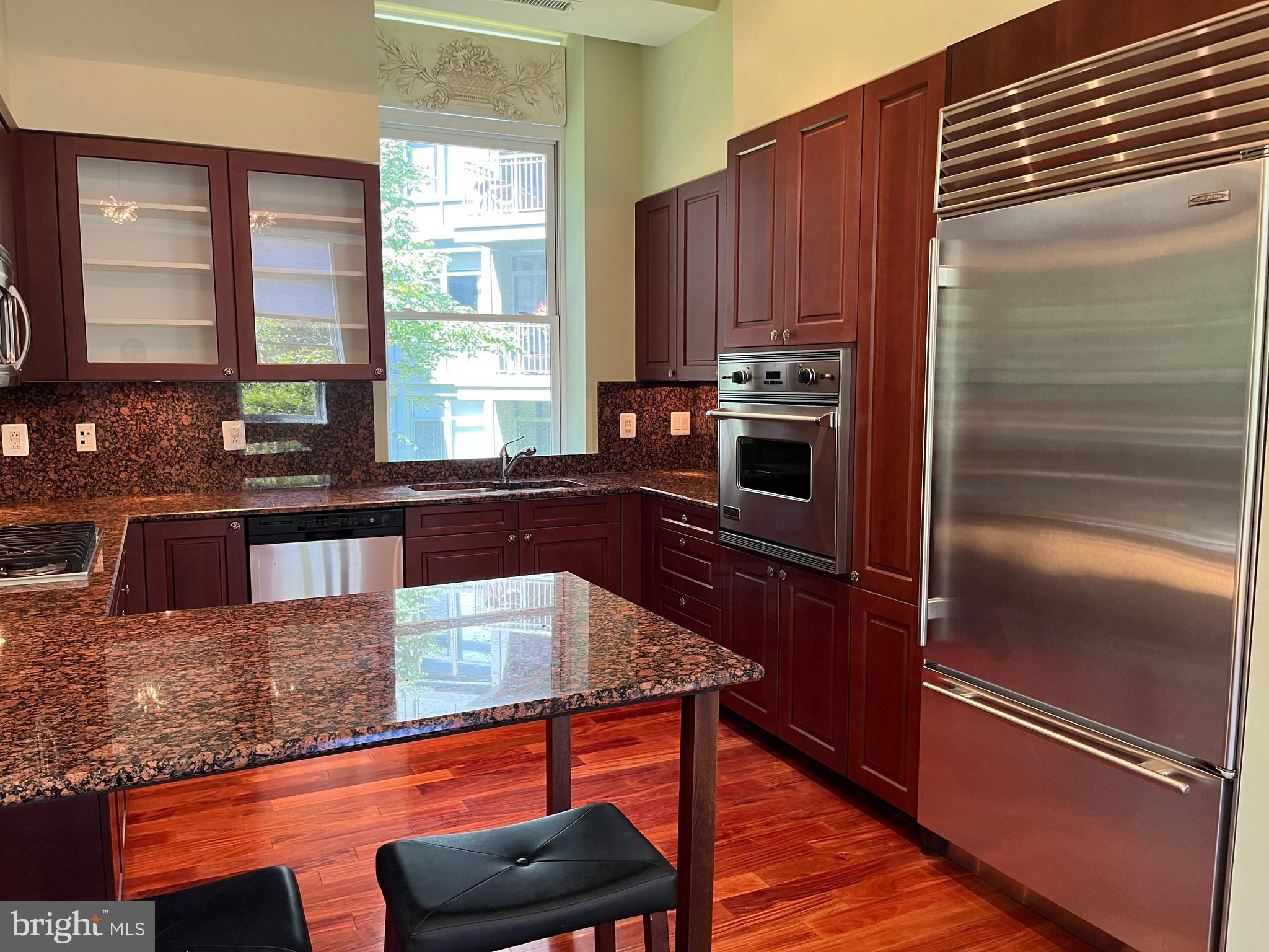 2425 L Street Northwest, Unit 215 Washington, DC 20037 - Photo 15 of 38 a kitchen with granite countertop a refrigerator and wooden cabinets